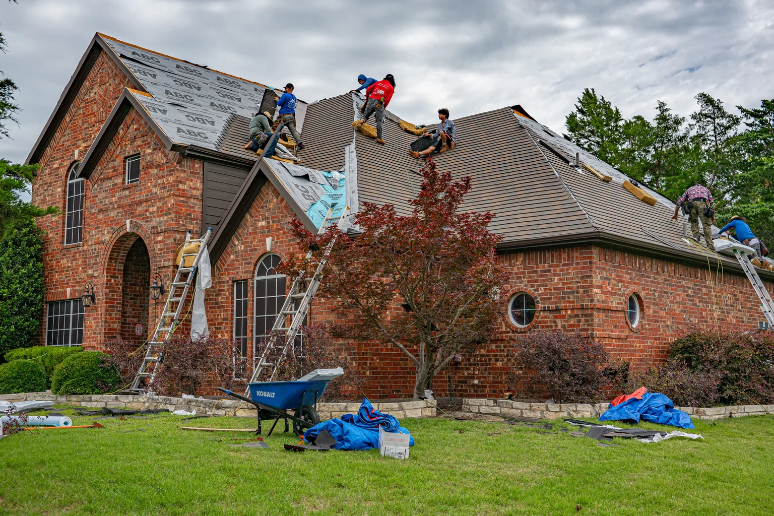 Roofing crew working on the roof of a large brick home